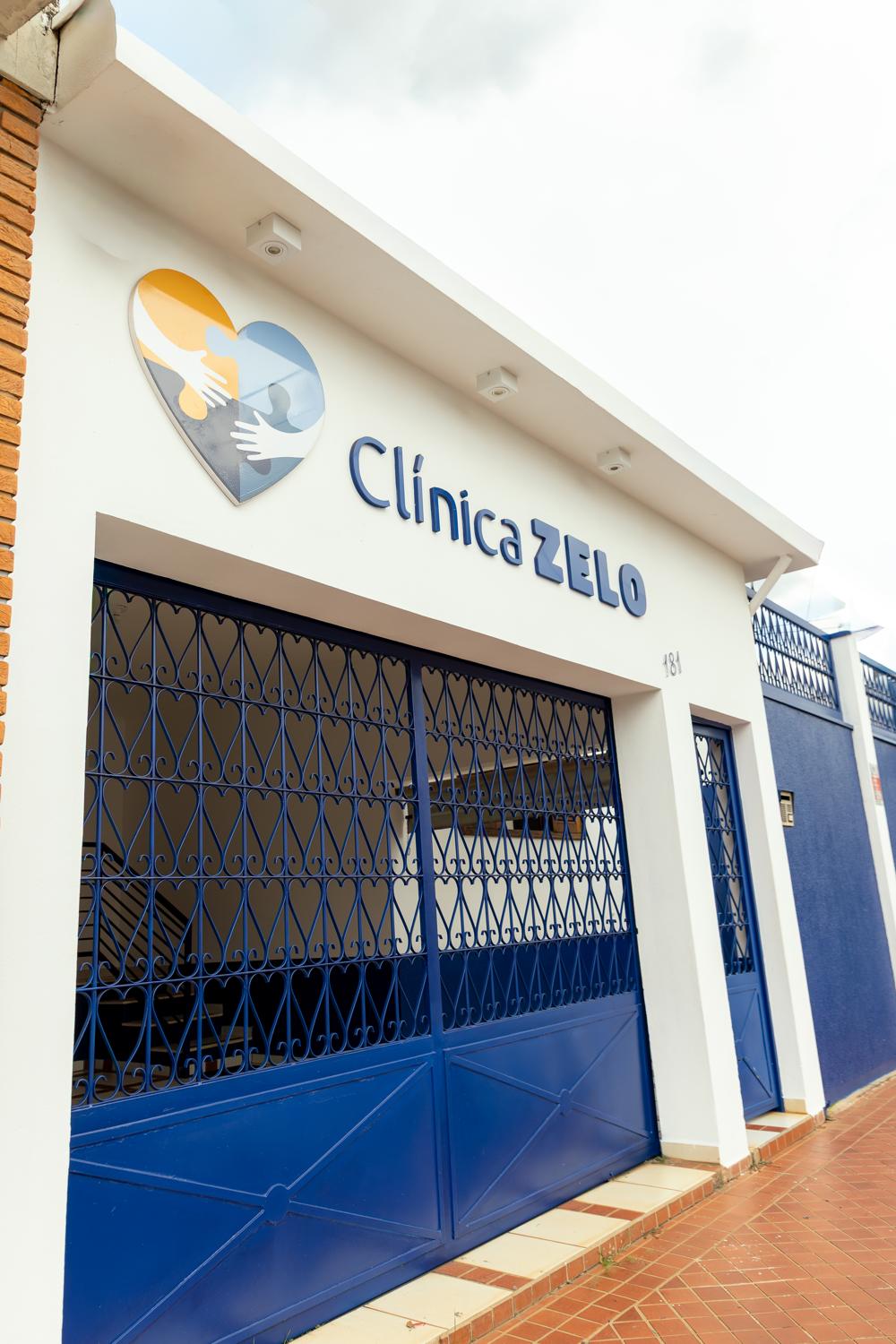 Fachada da Clínica Zelo, com o logo de coração e o portão azul, na Rua Prefeito Marciliano, 181